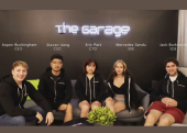 Five people sitting in front of a black wall bearing the words "The Garage."